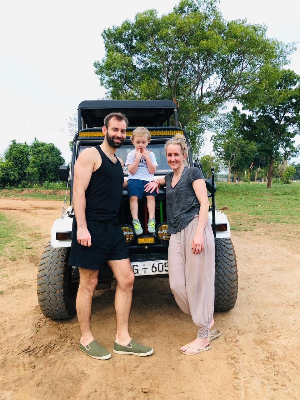 Family with young child posing in front of their private safari jeep at Udawalawe National Park