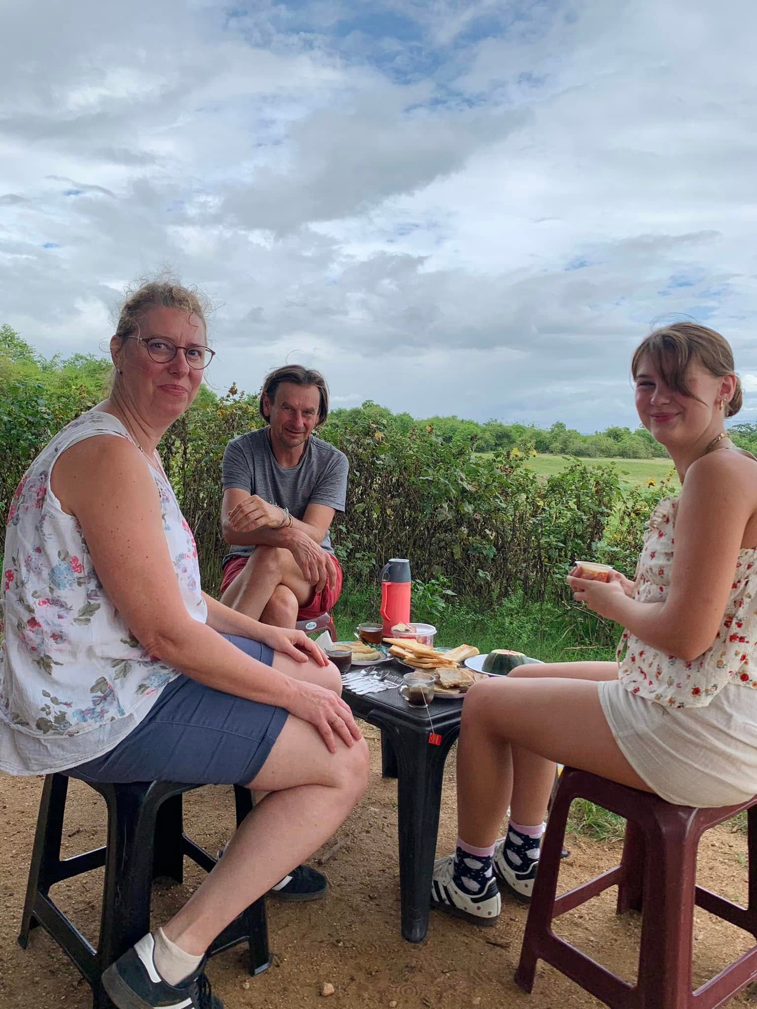 Safari guests relaxing on rocks with their jeep and Sri Lanka landscape behind them