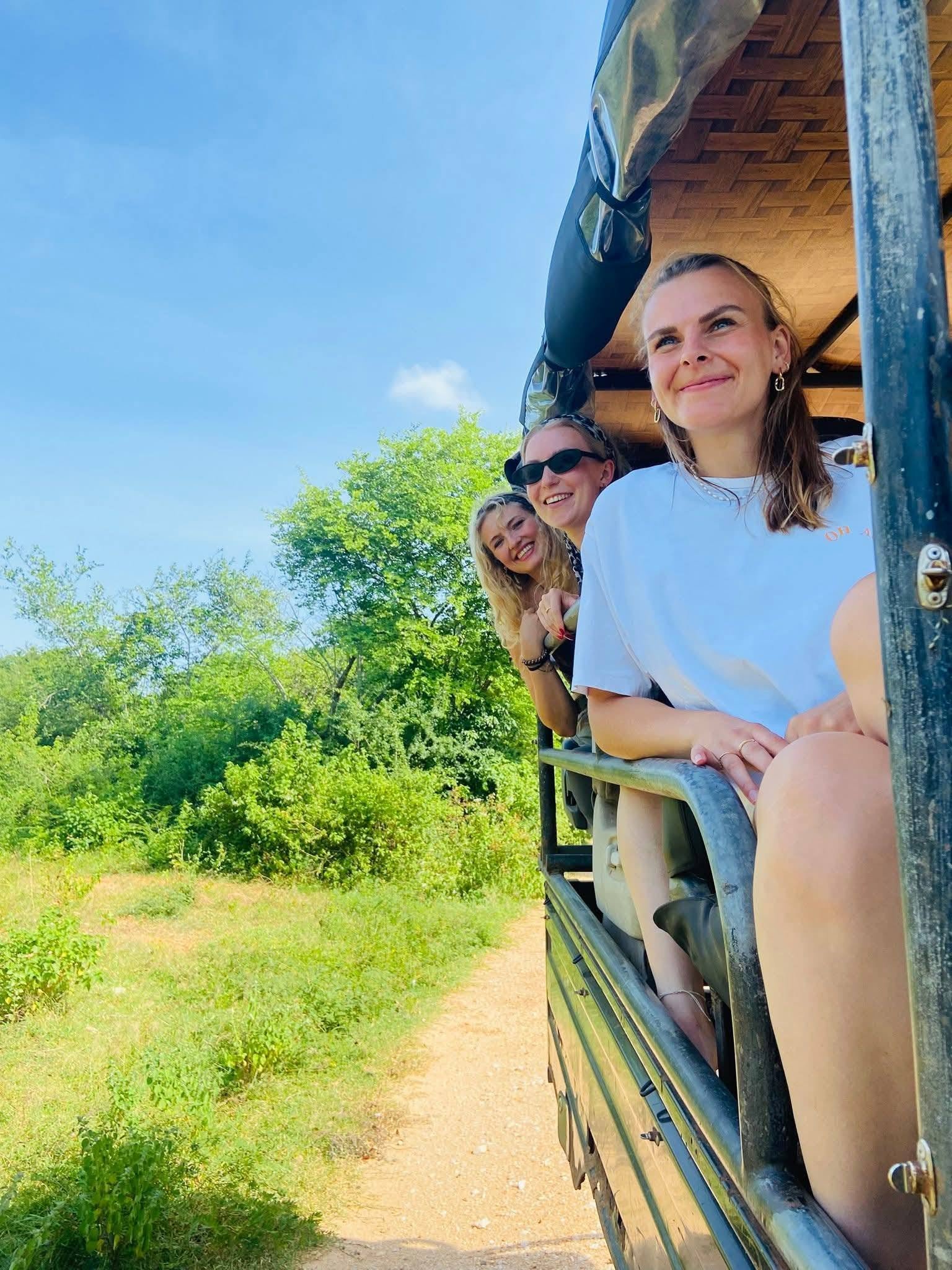Happy guests smiling inside the safari jeep surrounded by Udawalawe greenery